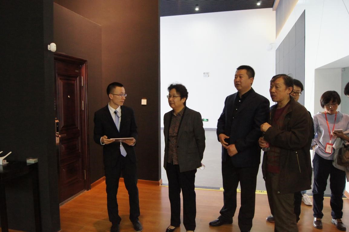 工作人员为姜风理事长演示智能门锁在生活中的应用